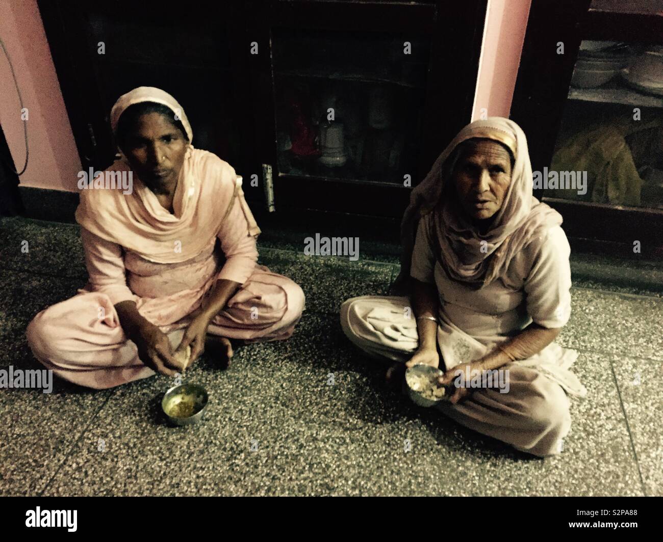Elderly Indian house keepers eating in Punjab, India Stock Photo