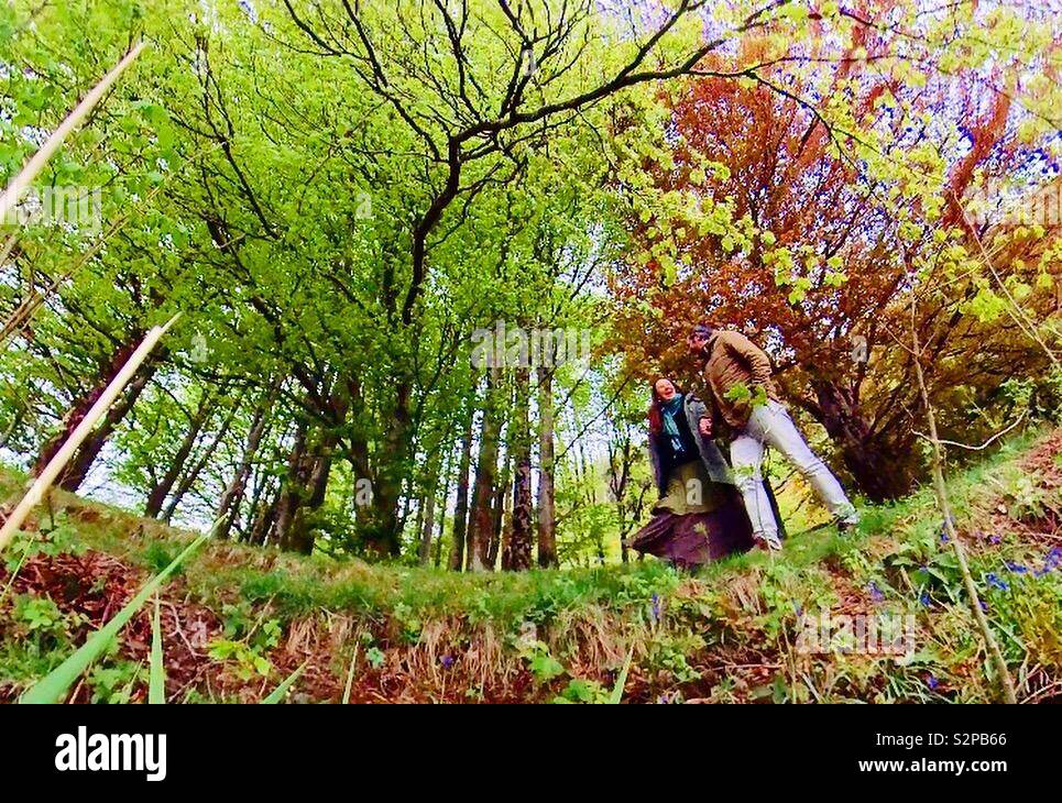 A couple walking under the trees in the woods Stock Photo - Alamy