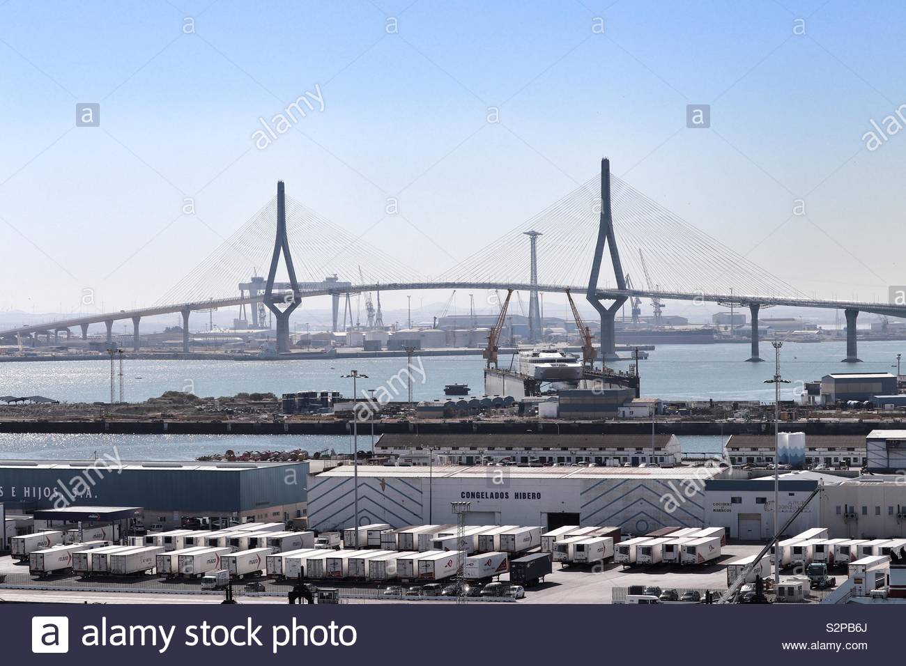 Industrial port with road bridge in background Stock Photo