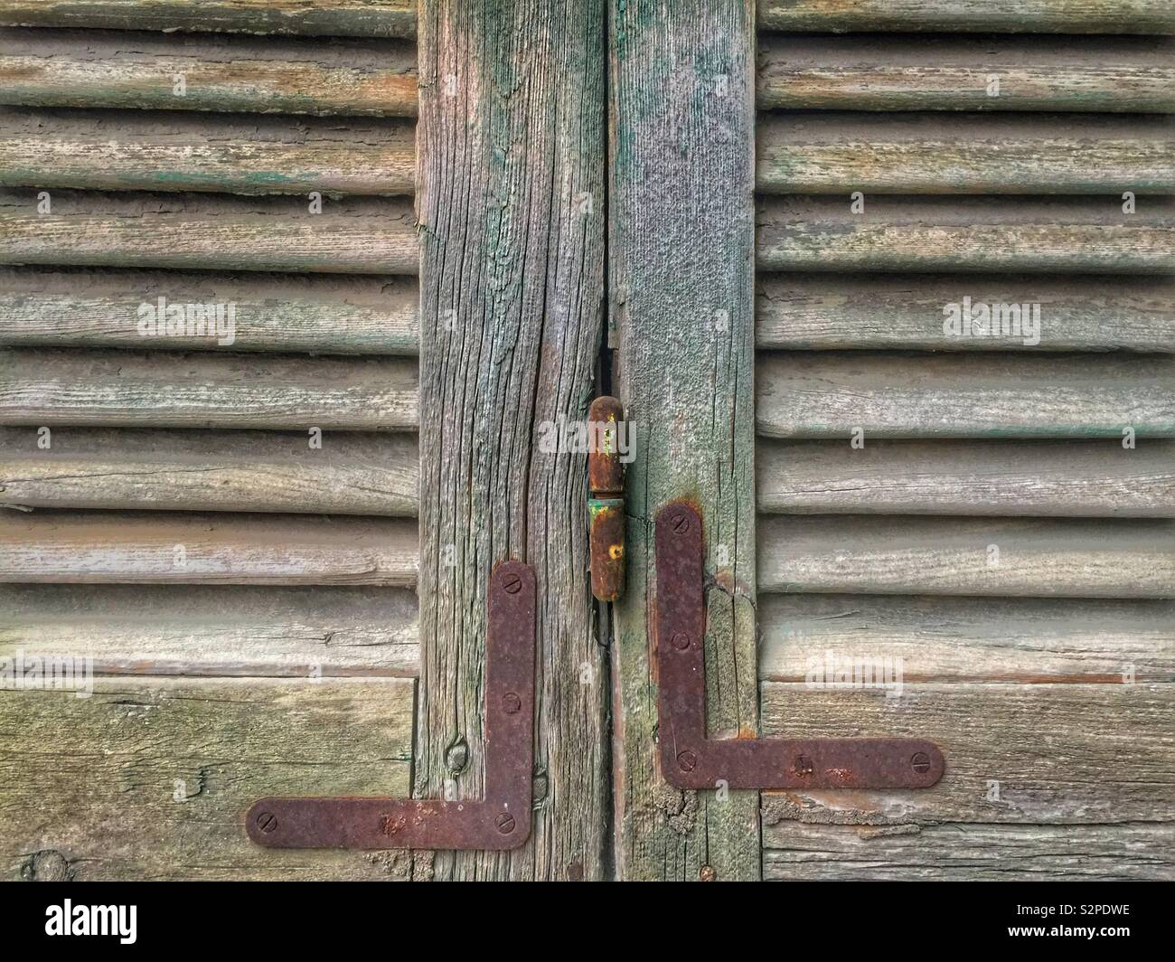 Old rusty hinge on wooden window shutters Stock Photo