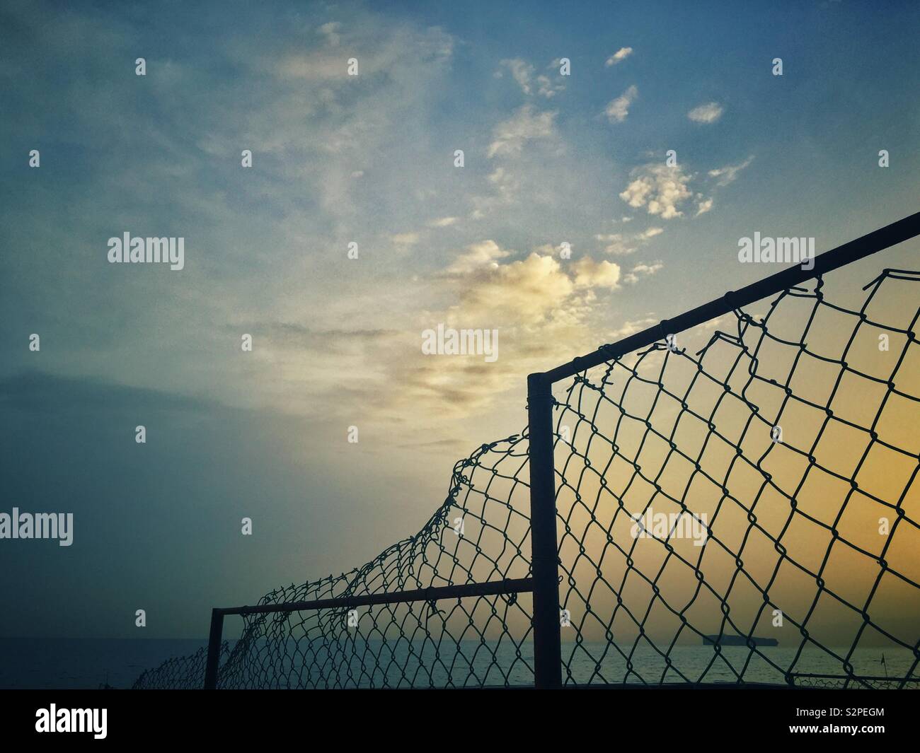 Broken chicken wire fence on the beach at sunrise Stock Photo