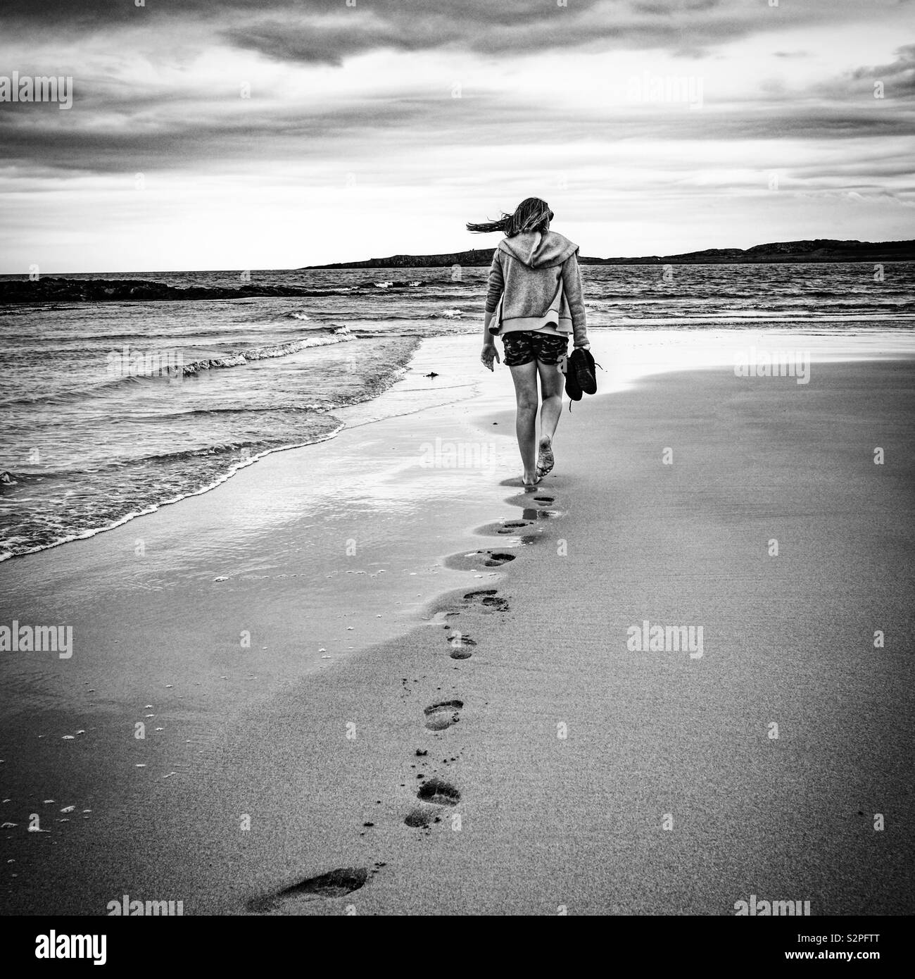 Girl walking on Embleton beach, Northumberland, England. Stock Photo