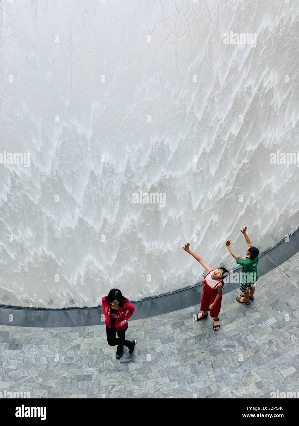 Posing woman and two children in front of waterfall at Jewel in Changi airport Singapore Stock Photo