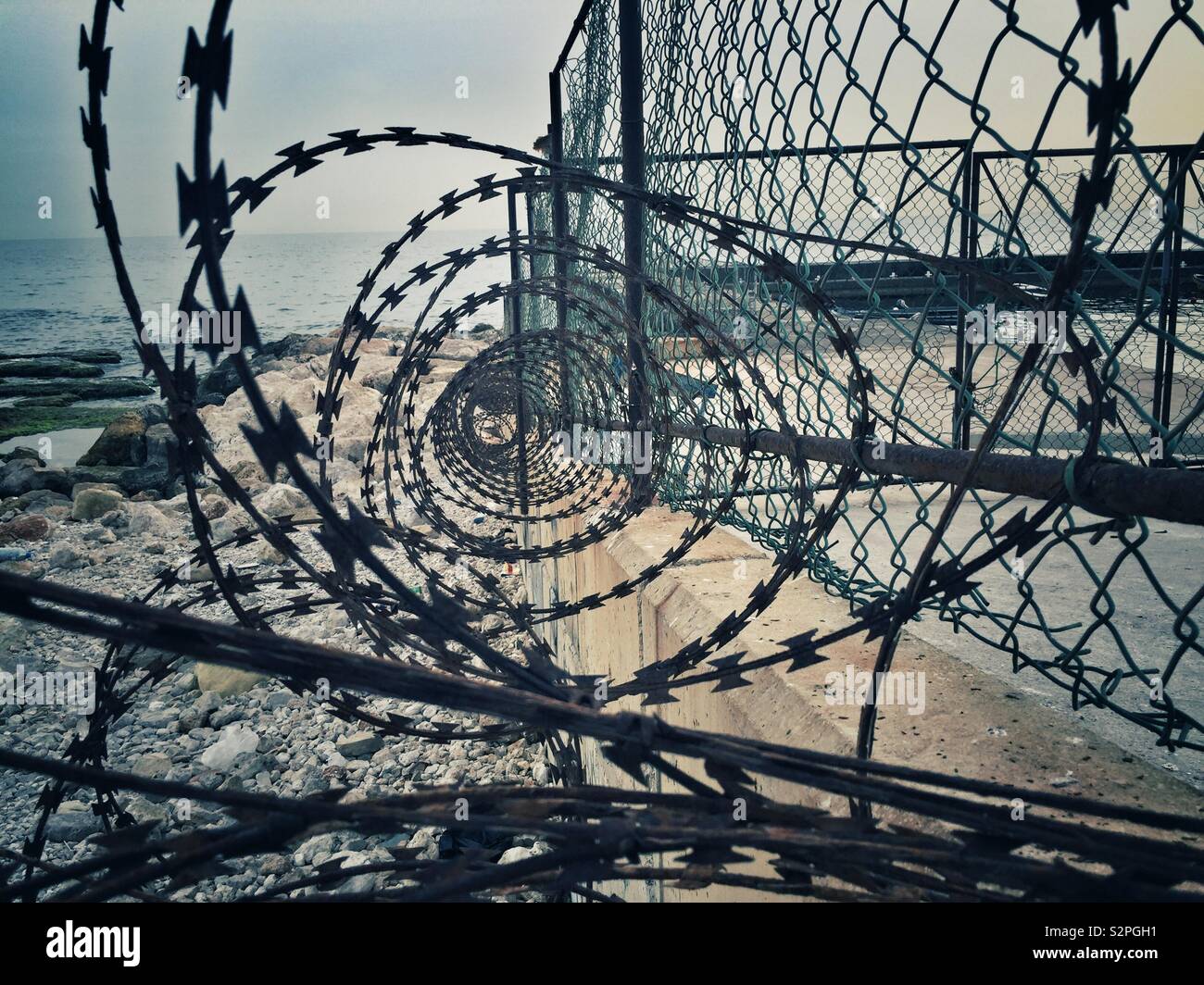 Spiral razor wire and fence on the beach Stock Photo