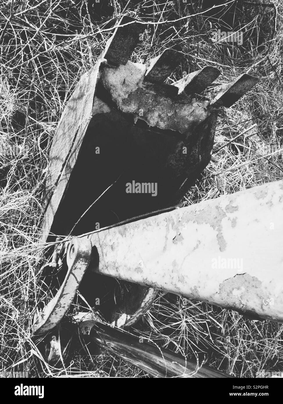 Black and white photo looking down the arm of a rusted backhoe into the bucket - Smartphone Captured Stock Image