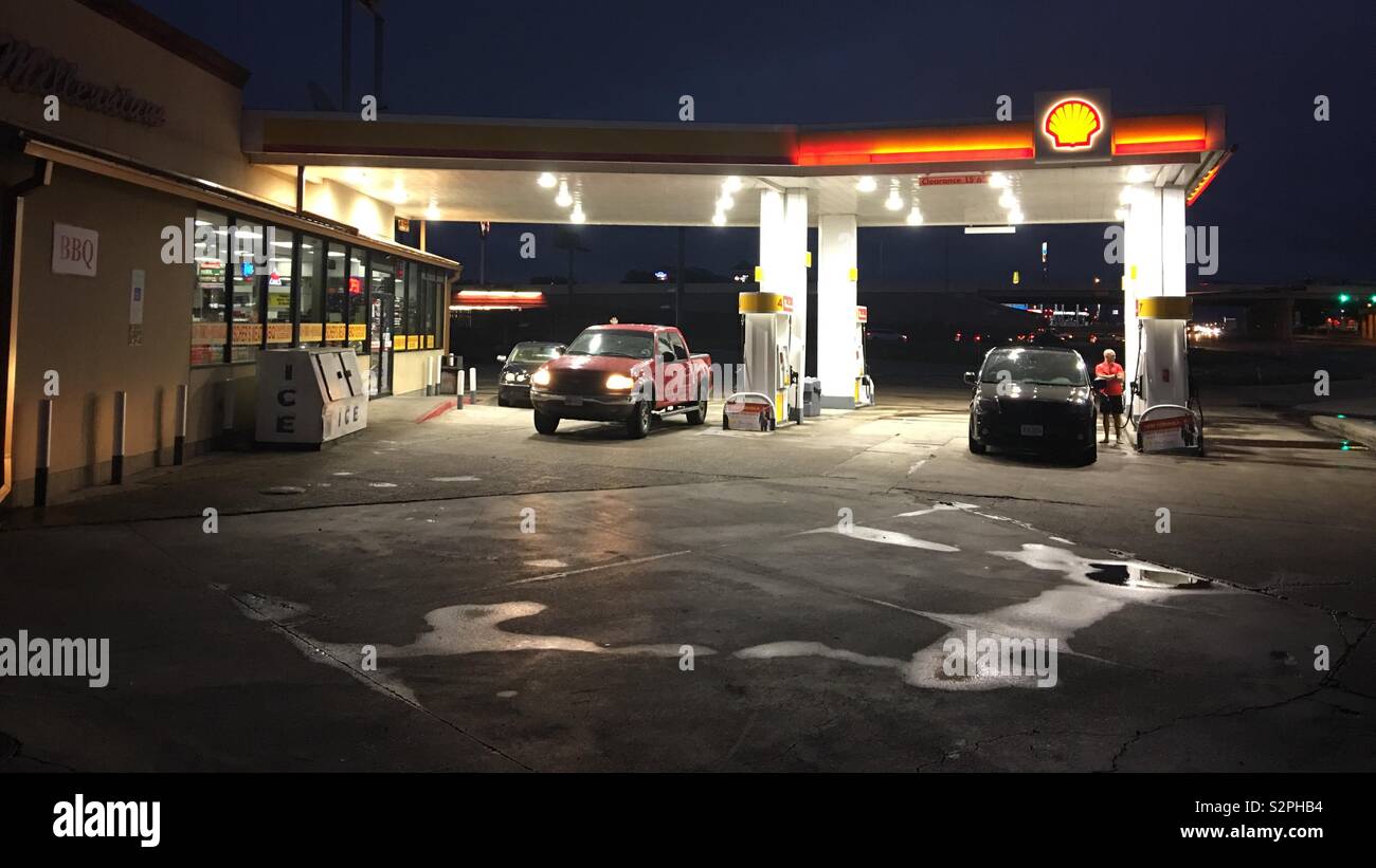 DENTON, TX, MAY 2019: Shell gas station with red pick up truck pulling out and SUV filling with gas at night after rain Stock Photo