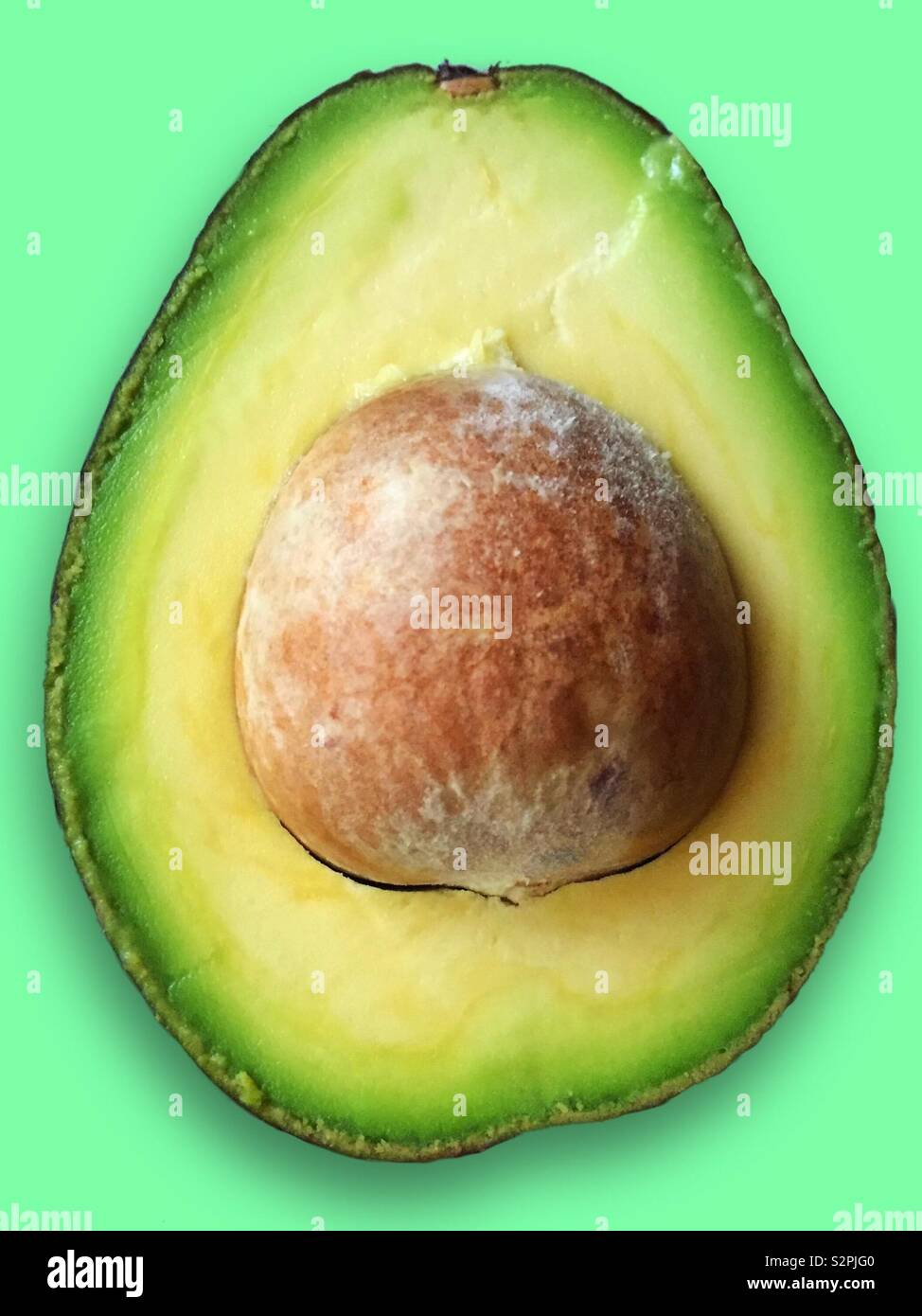 Fresh cut avocado with stone on a green background - Smartphone Captured Stock Image