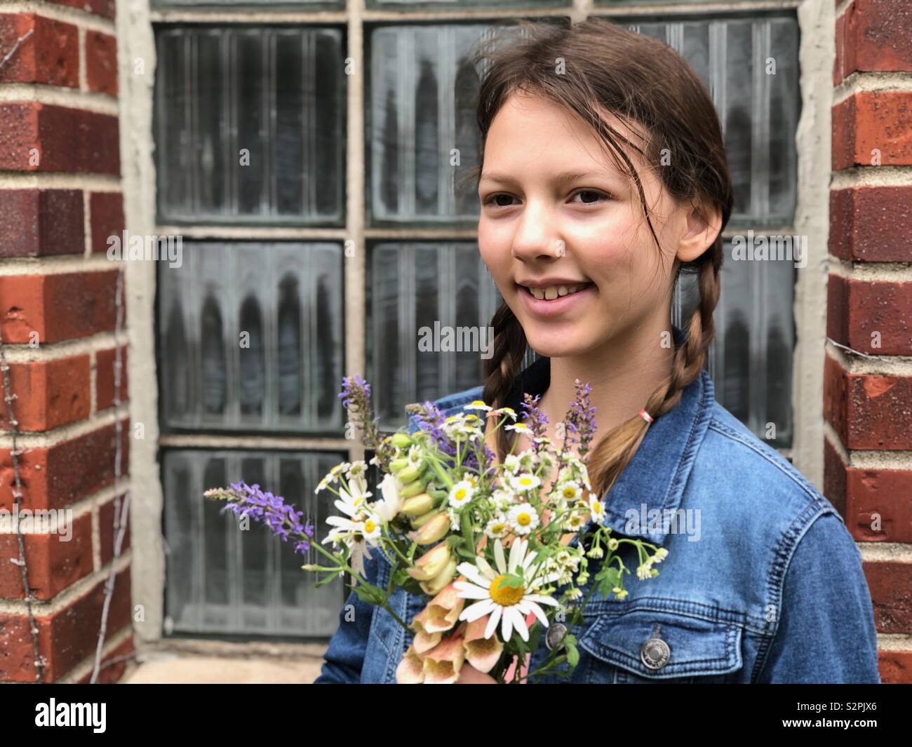 Pretty young girl with flowers in front of window Stock Photo Alamy