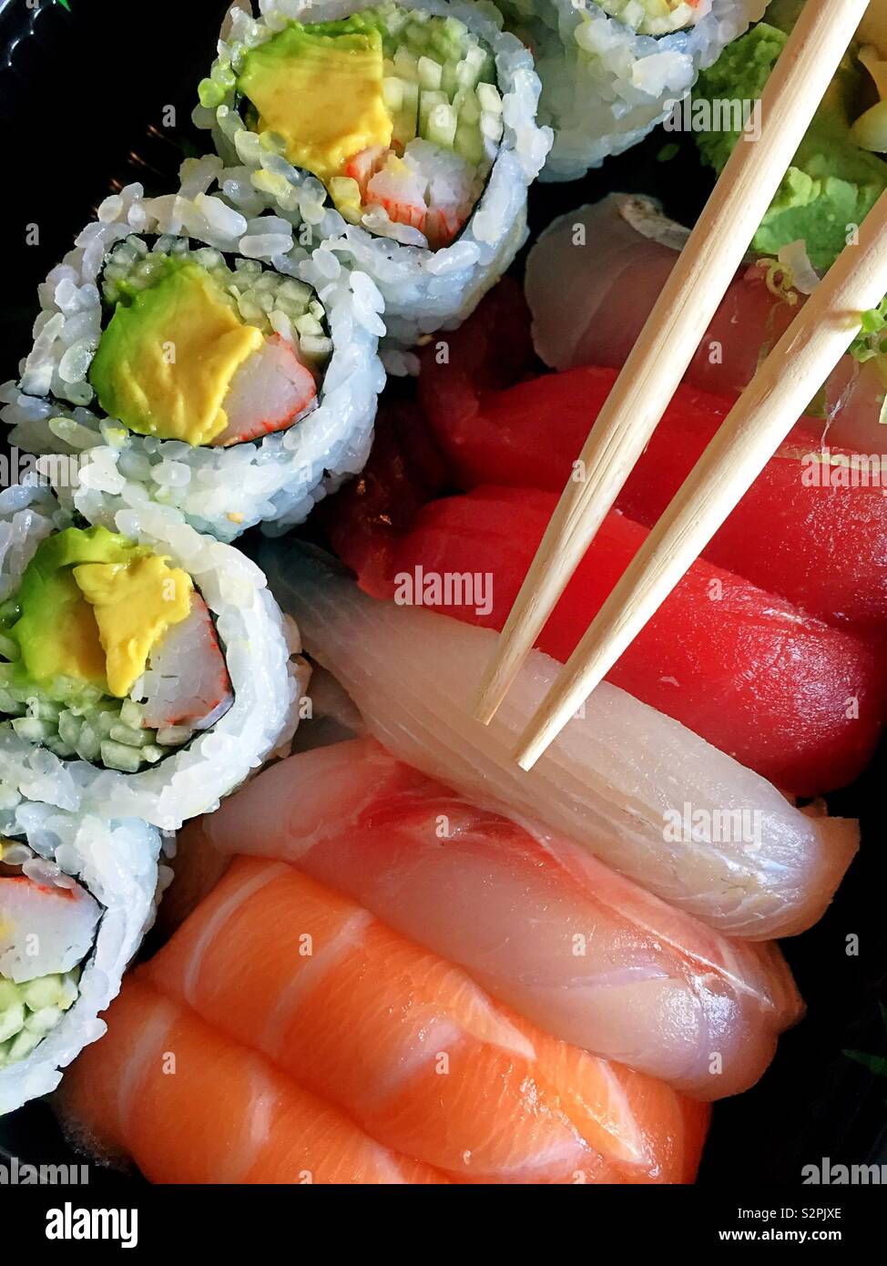 Close up of a California roll and pieces of sushi with chopsticks - Smartphone Captured Stock Image