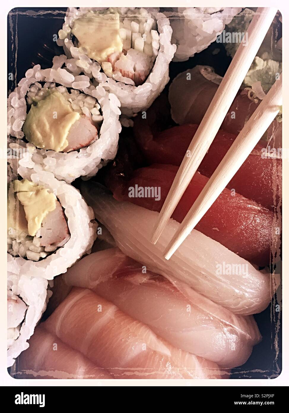 A Japanese delivery meal of sushi pieces and California roll with chopsticks, New York City, USA - Smartphone Captured Stock Image