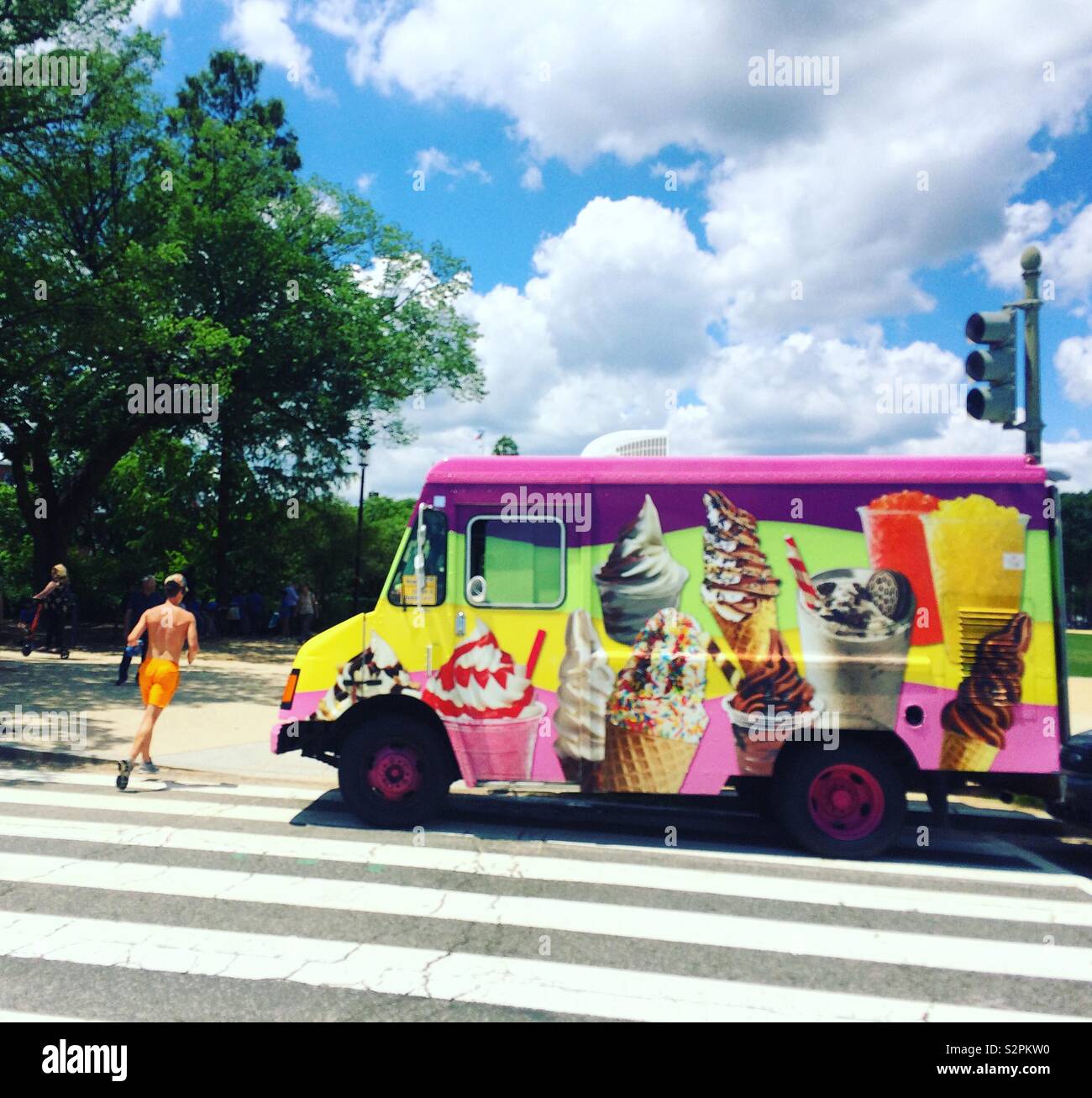 A man in orange shorts jogs past an ice cream truck at the National Mall in Washington, D.C., United States - Smartphone Captured Stock Image
