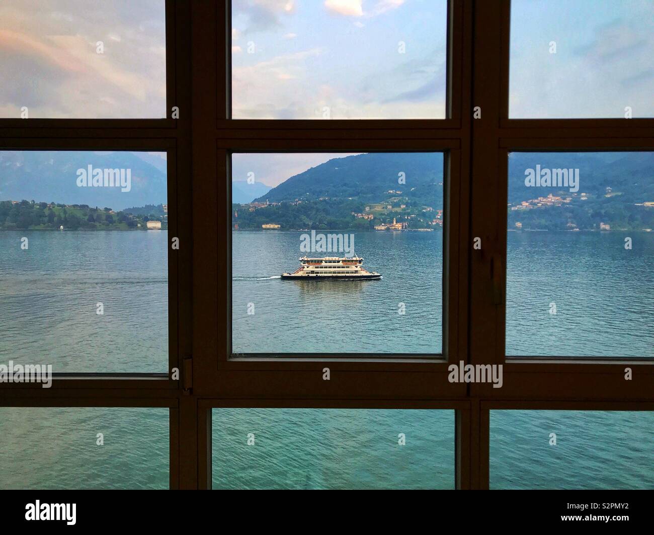 Ferry on Lake Como seen through the windows of a lakeside hotel - Smartphone Captured Stock Image