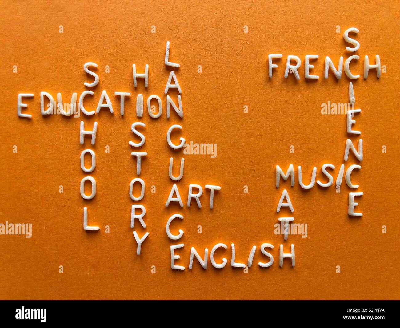 Words including education, school, history, language, art, English, math, music, science and French on a bright orange background. - Smartphone Captured Stock Image