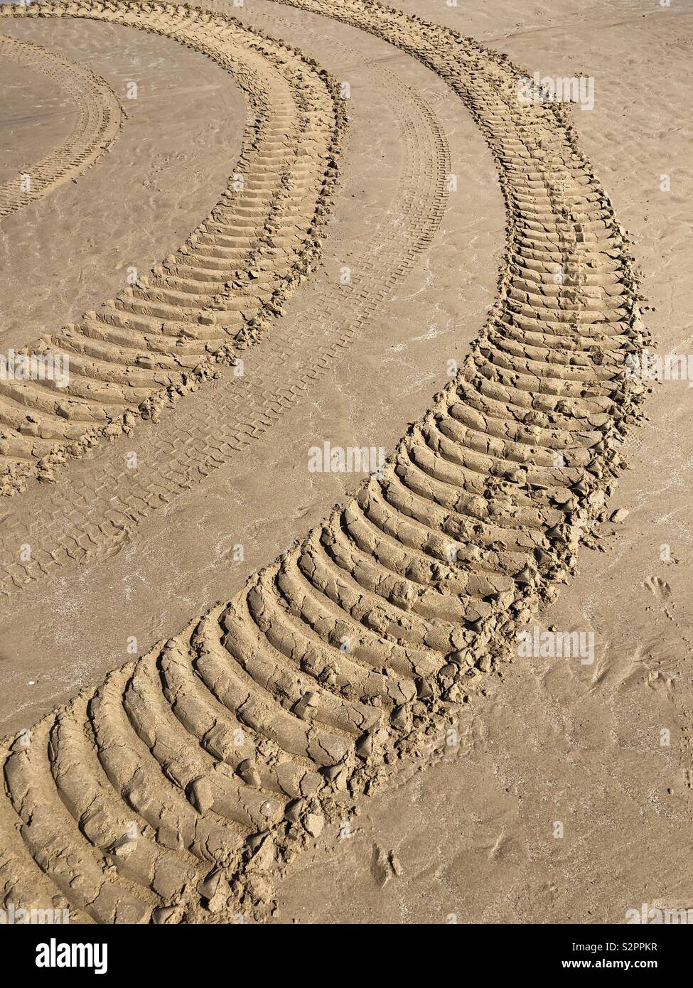 Wide caterpillar tracks on a sandy beach Stock Photo
