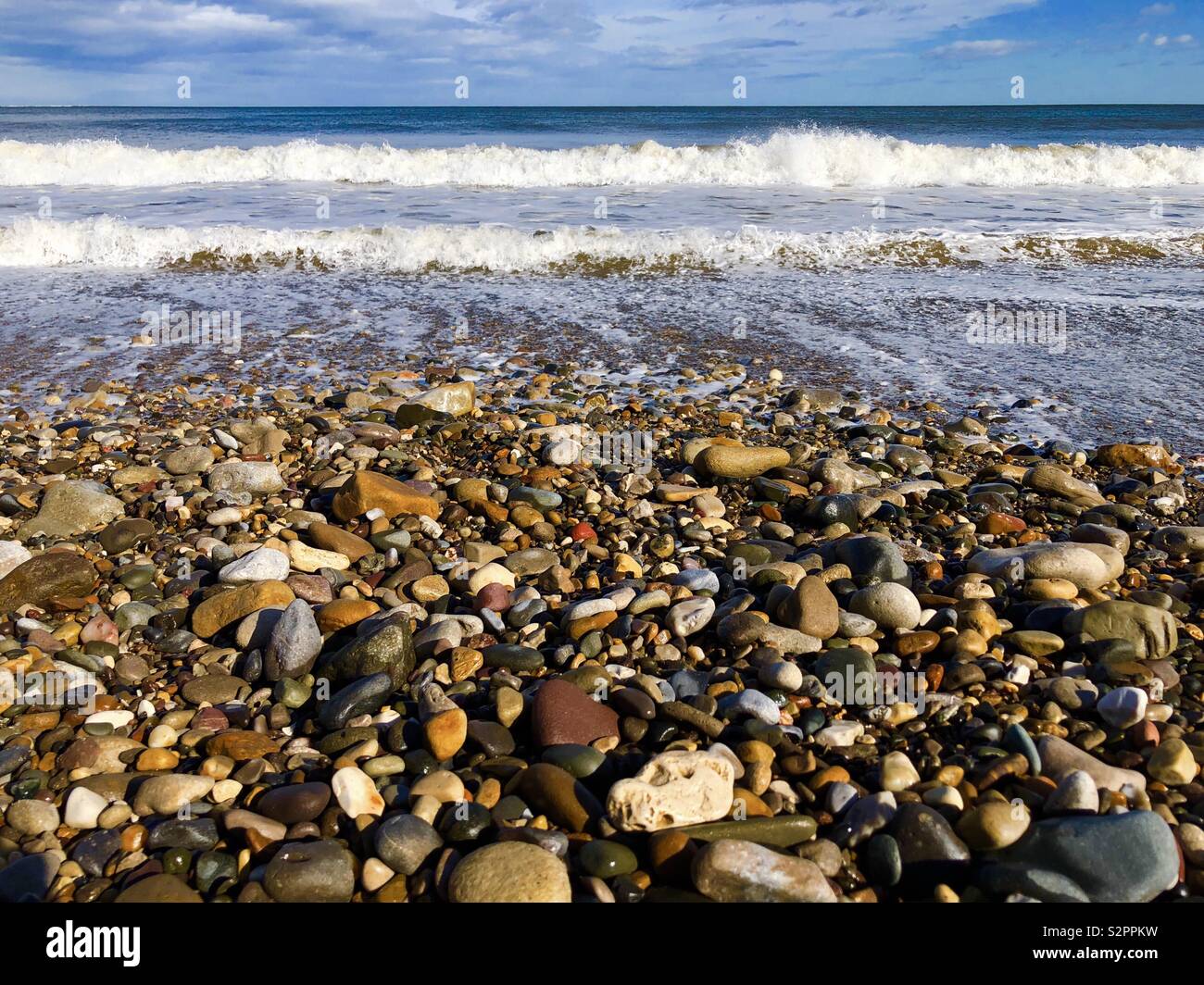 Wet Pebbles and waves on a beach viewed from a low angle - Smartphone Captured Stock Image