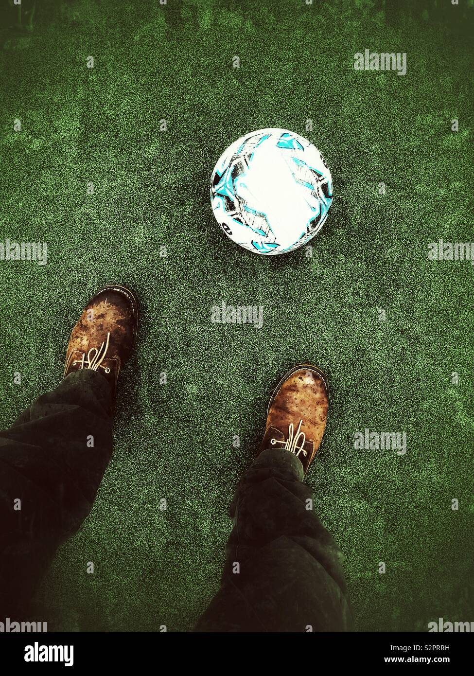 Man standing over a football on an artificial sports pitch - Smartphone Captured Stock Image