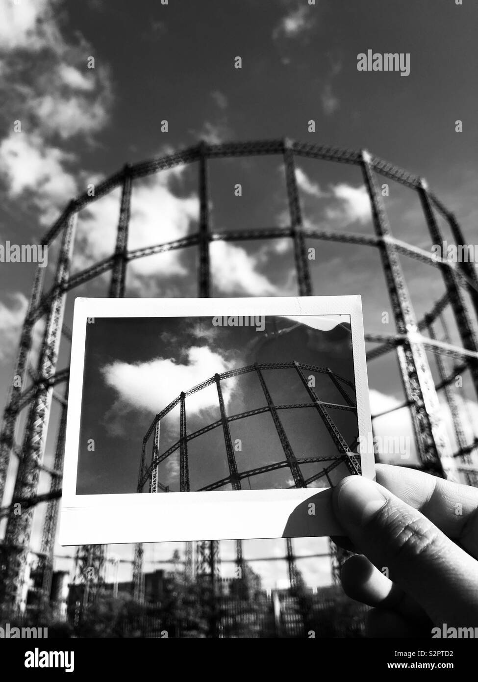 Man holding an instant photograph of a gas holder in East London UK - Smartphone Captured Stock Image