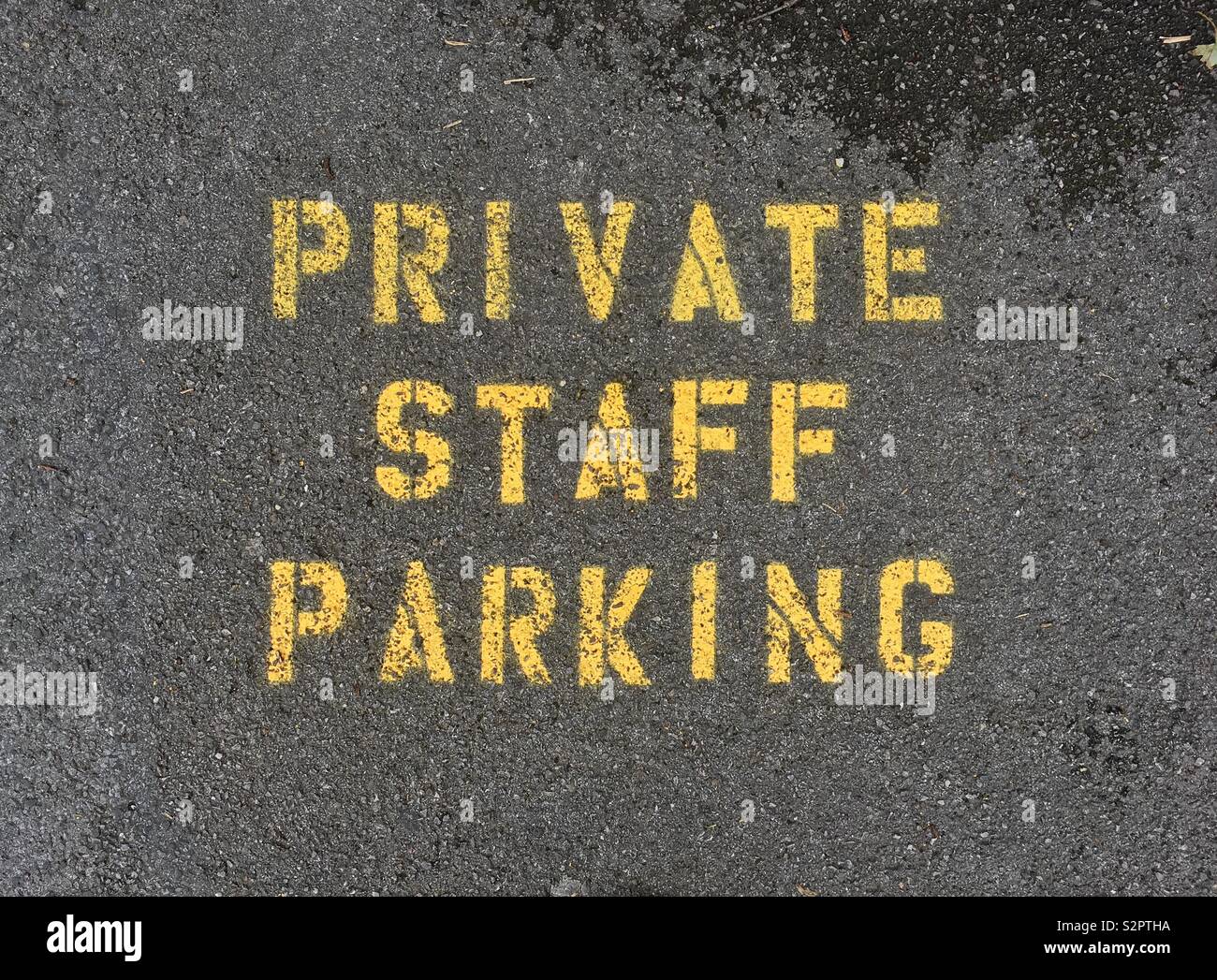 A sign reading “PRIVATE STAFF PARKING” spray-painted on a pavement Stock Photo