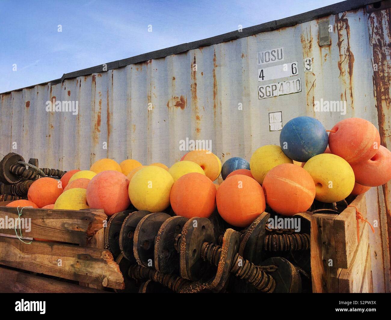 Colourful, round fishing floats stored beside a metal container - Smartphone Captured Stock Image