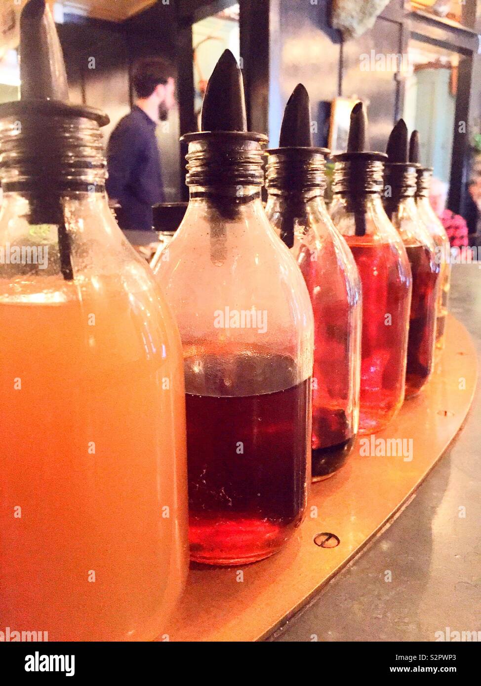 Flavored syrup bottles aligned on a bar top in a restaurant, USA - Smartphone Captured Stock Image