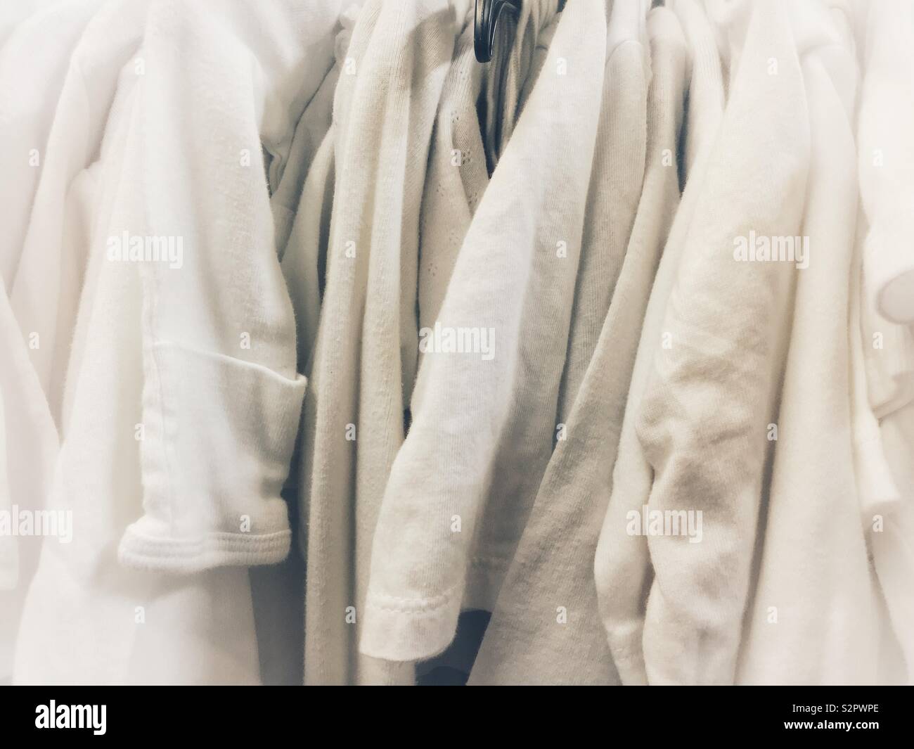 Bunch of white cotton clothes hanging on a rod in soft focus. Stock Photo