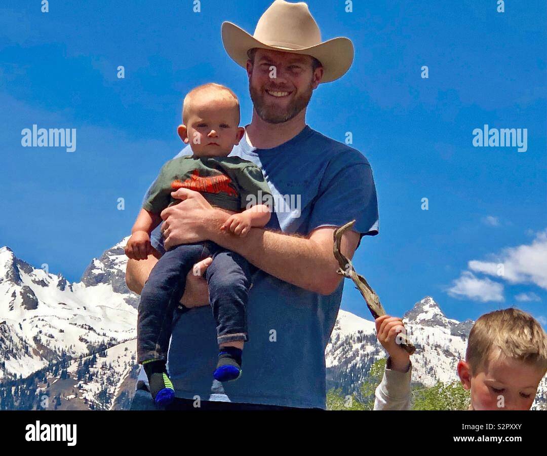 Proud father holding son with the grand Teton mountains of Wyoming in the background Stock Photo