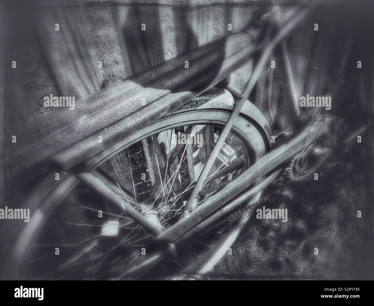 Rusty vintage bicycle parked against a wooden fence Stock Photo