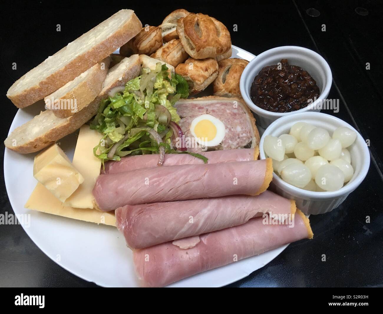 Ploughman’s lunch with ham cheese sausage rolls pickle pickles onions