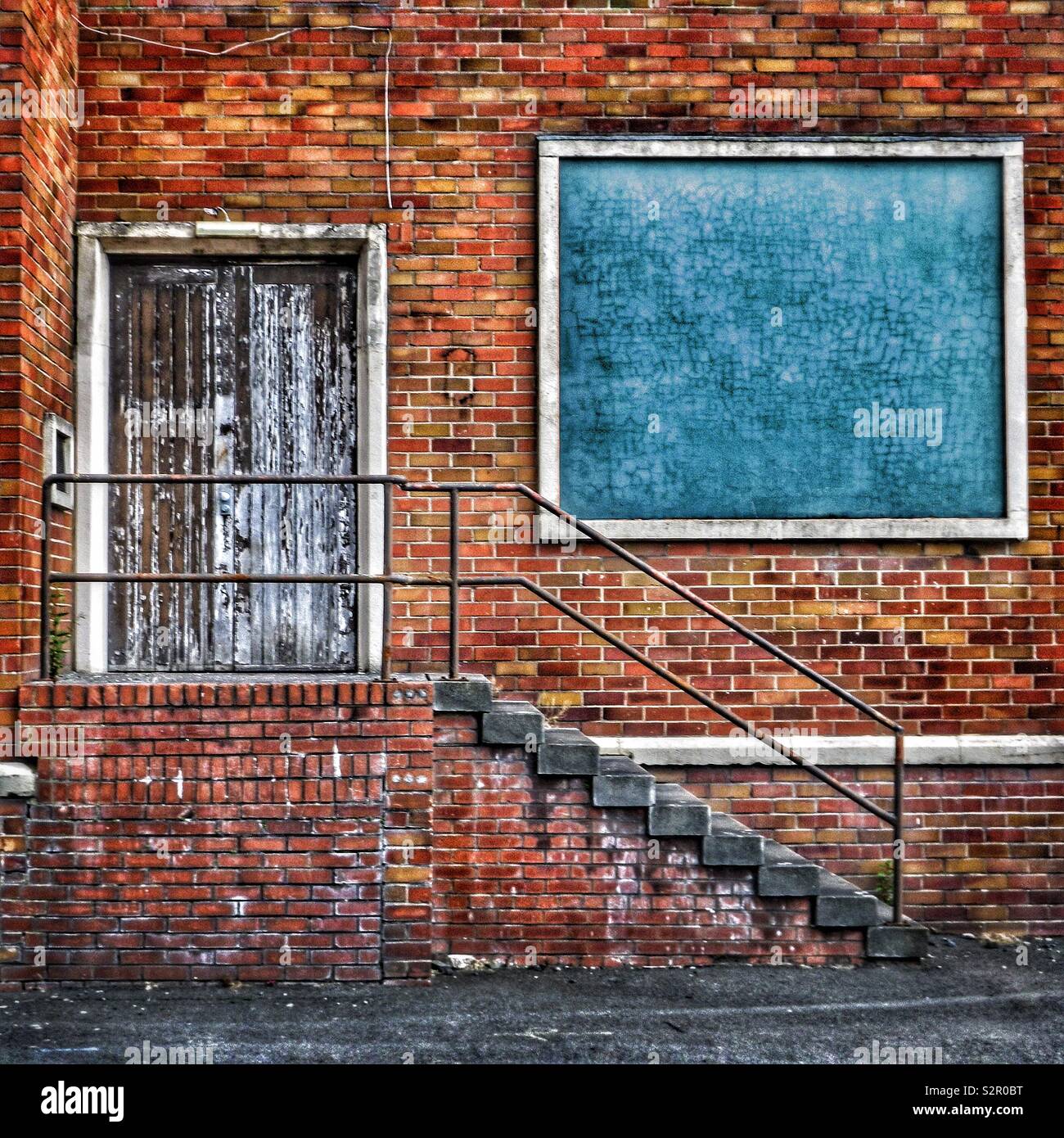 Blue window in an old factory with stairway and closed access door - Smartphone Captured Stock Image