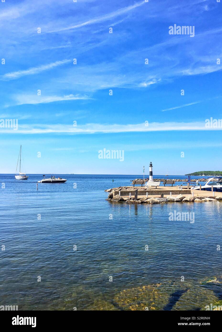 Pier and small black and white lighthouse against blue summer sky on Lake Michigan at Sister Bay, WI - Smartphone Captured Stock Image