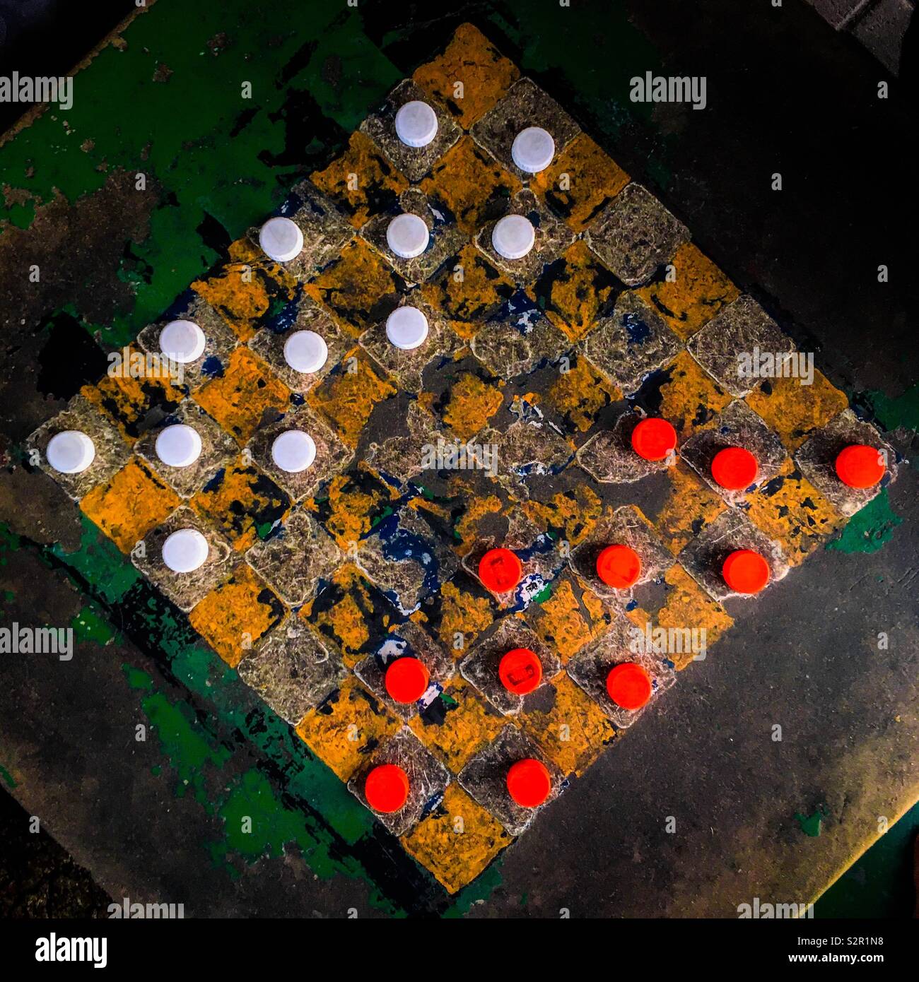 Plastic bottle caps (checkers pieces) are seen positioned before the game begins on an outdoor checkerboard table in the park in San Salvador, El Salvador, 26 November 2018. Stock Photo