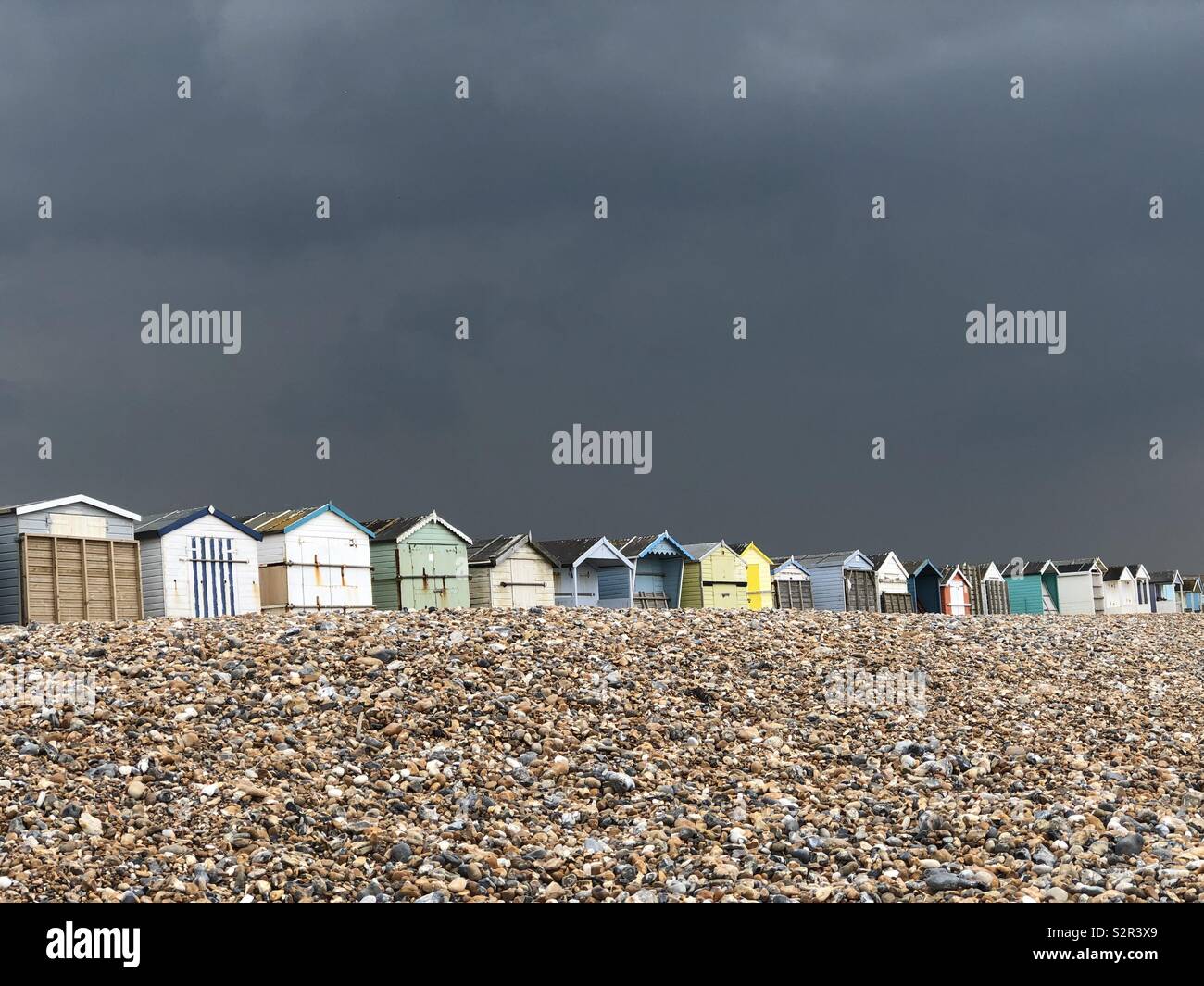 A dark stormy sky over some beach huts on the coast at Lancing, West Sussex, UK. Stock Photo