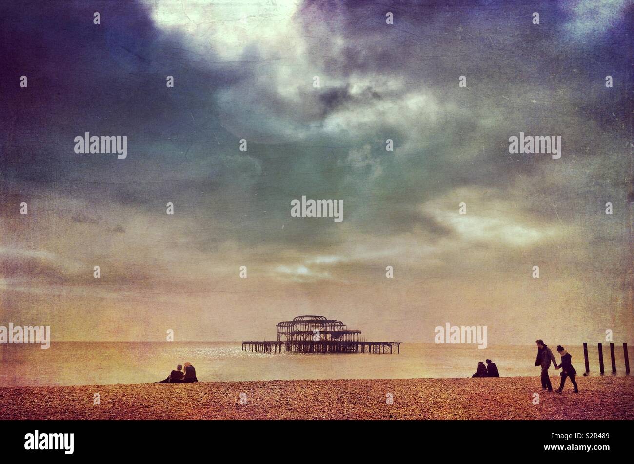 Couples on Brighton beach with a view of the ruined West Pier out to sea - Smartphone Captured Stock Image