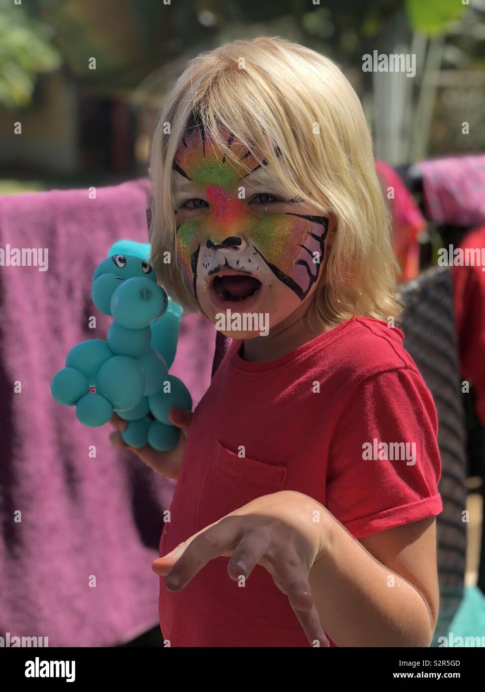 7 year old girl enjoys face paints and balloon animals at a birthday party Stock Photo