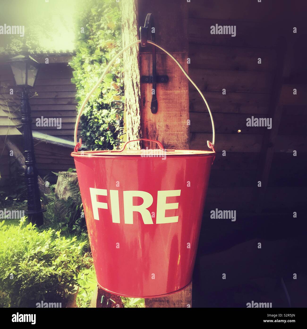 Red fire bucket, Medstead, Alton, Hampshire,England, United Kingdom. - Smartphone Captured Stock Image
