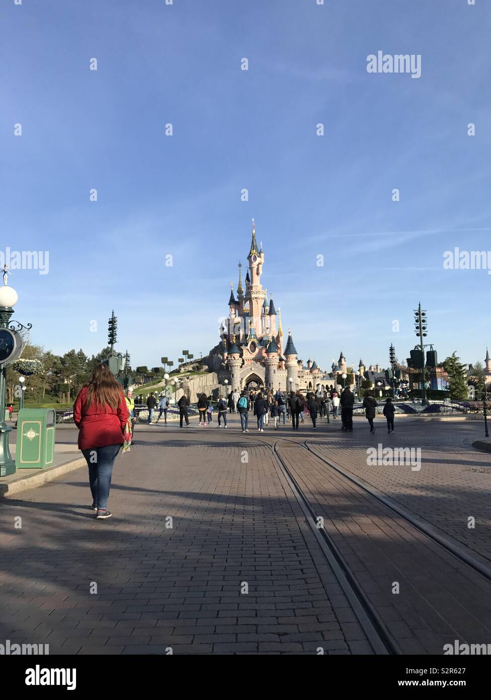 Adult woman wearing red walking to Disneyland Princess Castle in Paris Spring time Stock Photo