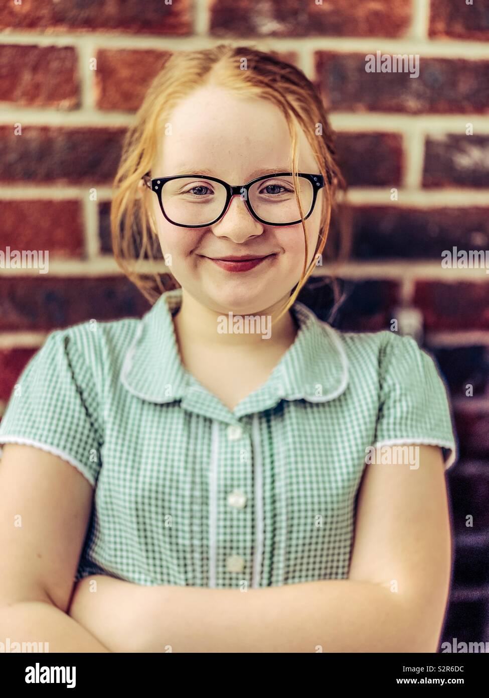 Young 9 year old girl posing next to a brick wall Stock Photo