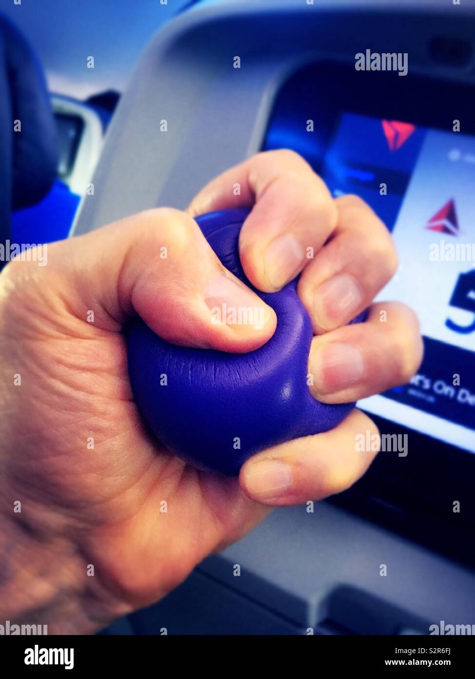 Man gripping a stress ball in flight to relieve fear of flying, USA - Smartphone Captured Stock Image