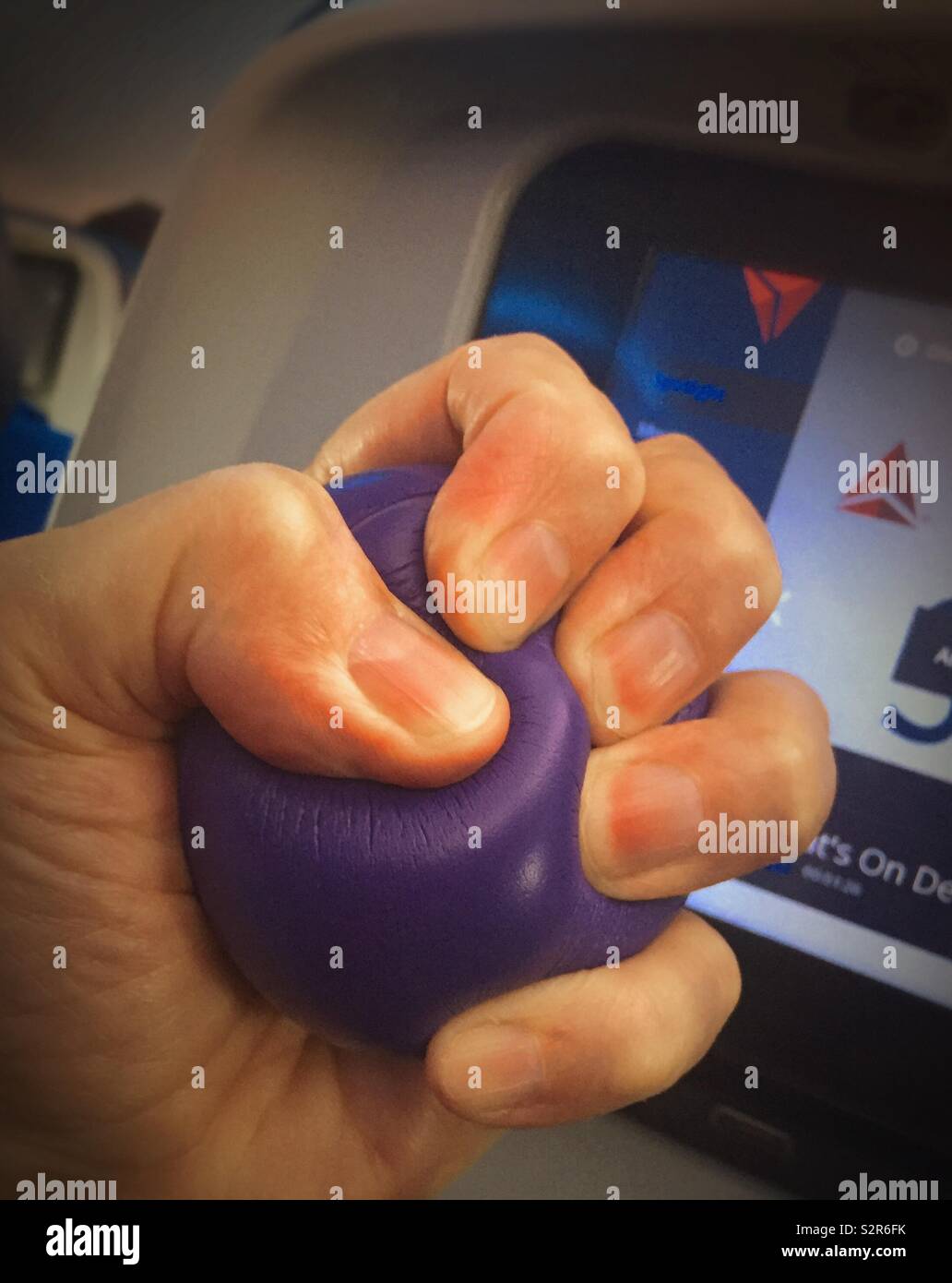 Man gripping stress ball in flight to relieve fear of flying, USA - Smartphone Captured Stock Image