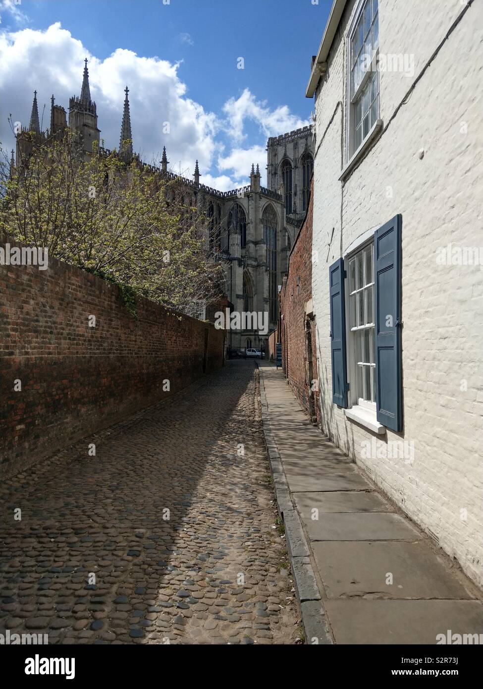 A cobbled street in York leading to the magnificent gothic splendour of York Minster Stock Photo
