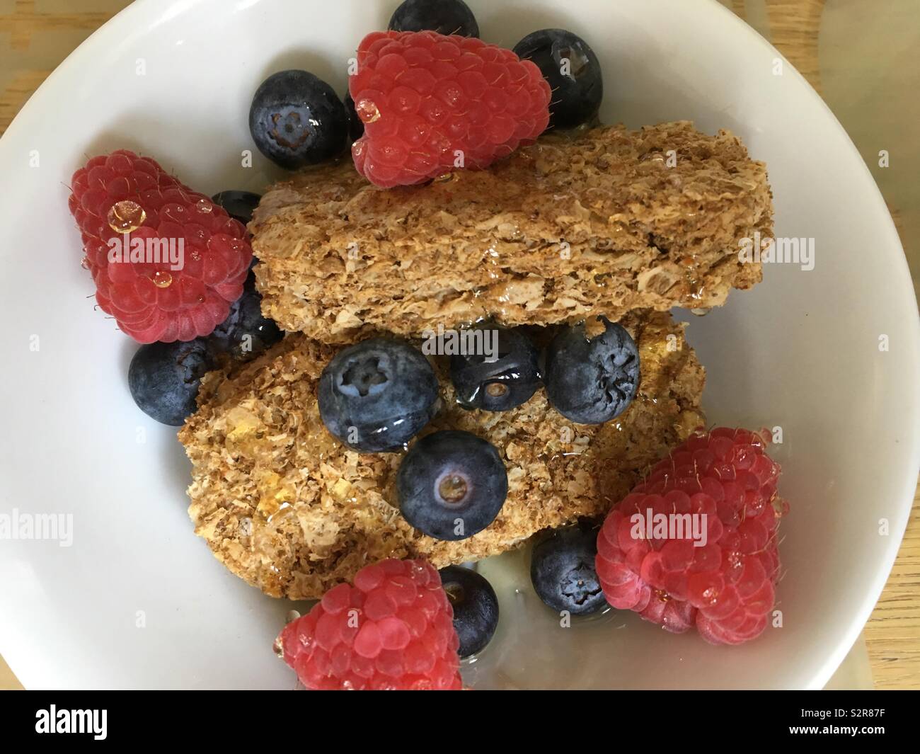 Healthy bowl of wheat biscuits with raspberry, blueberry and honey - Smartphone Captured Stock Image