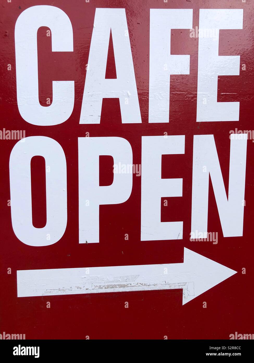 Cafe open sign - white upper case letters on red, painted background with arrow pointing to the right Stock Photo