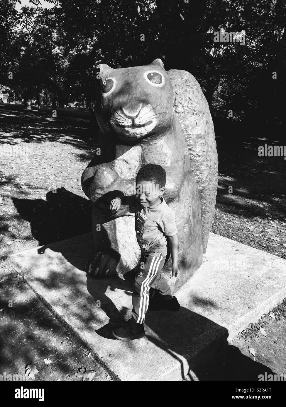 Child In Black And White Standing Next To Big Squirrel Stock Photo