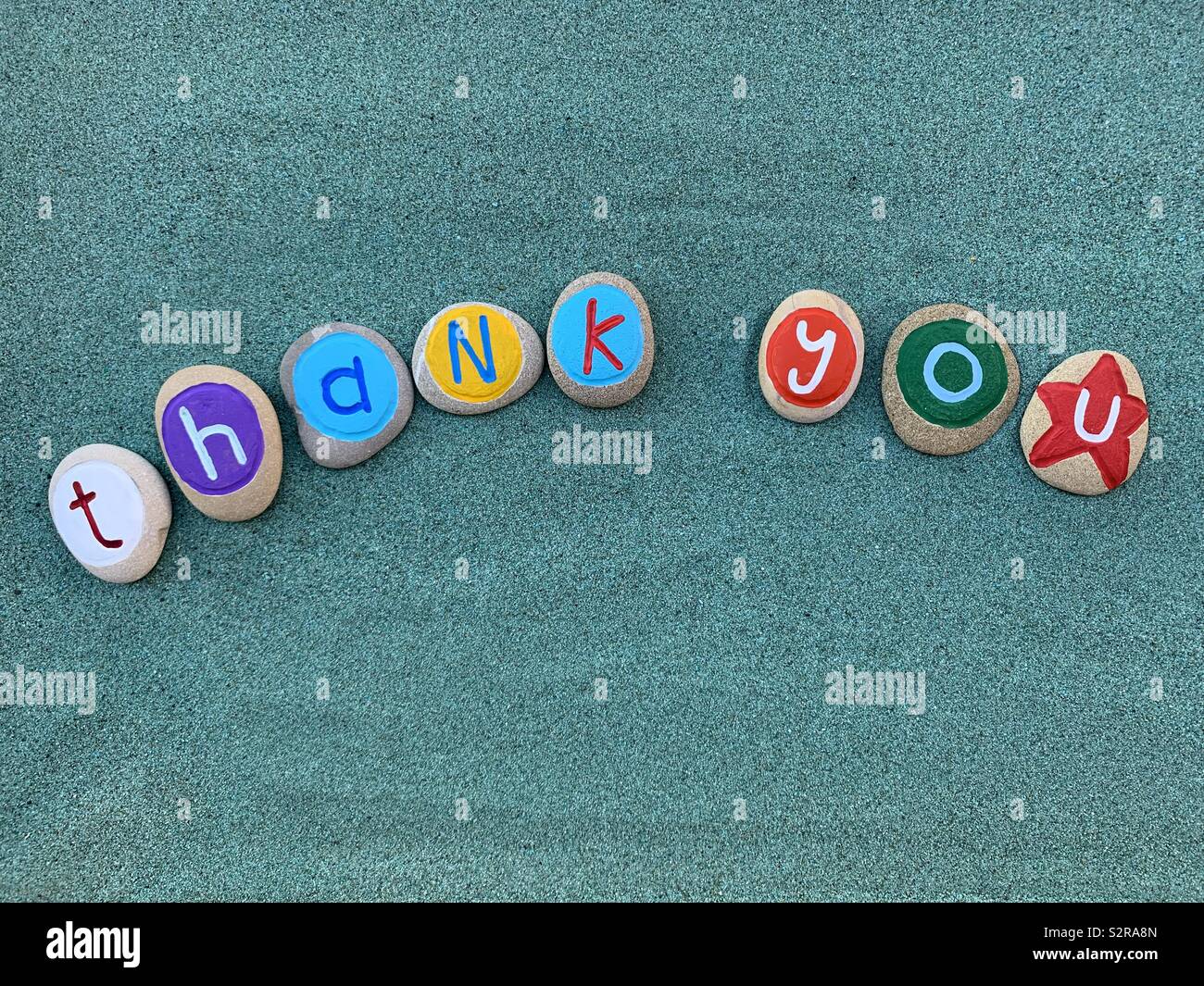 Thank you text with colored pebbles over green sand - Smartphone Captured Stock Image