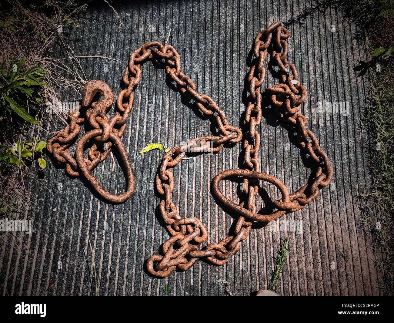Rusted logging chain strewn across rubber truck mat - Smartphone Captured Stock Image