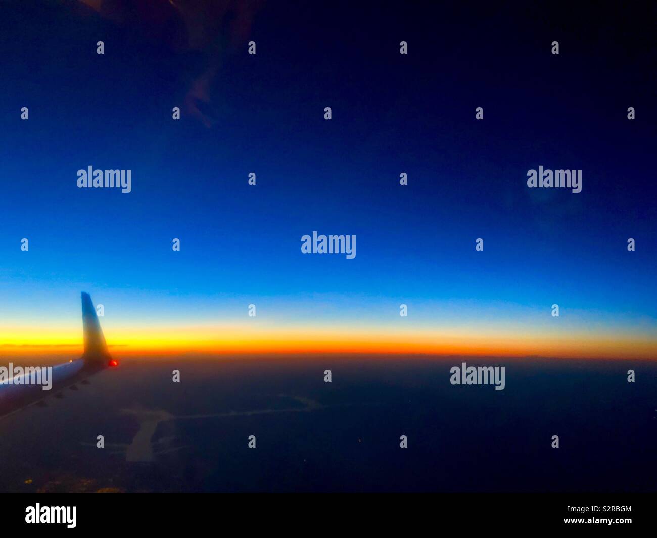 Brilliantly colored horizon viewed from a plane window with wingtip visible Stock Photo