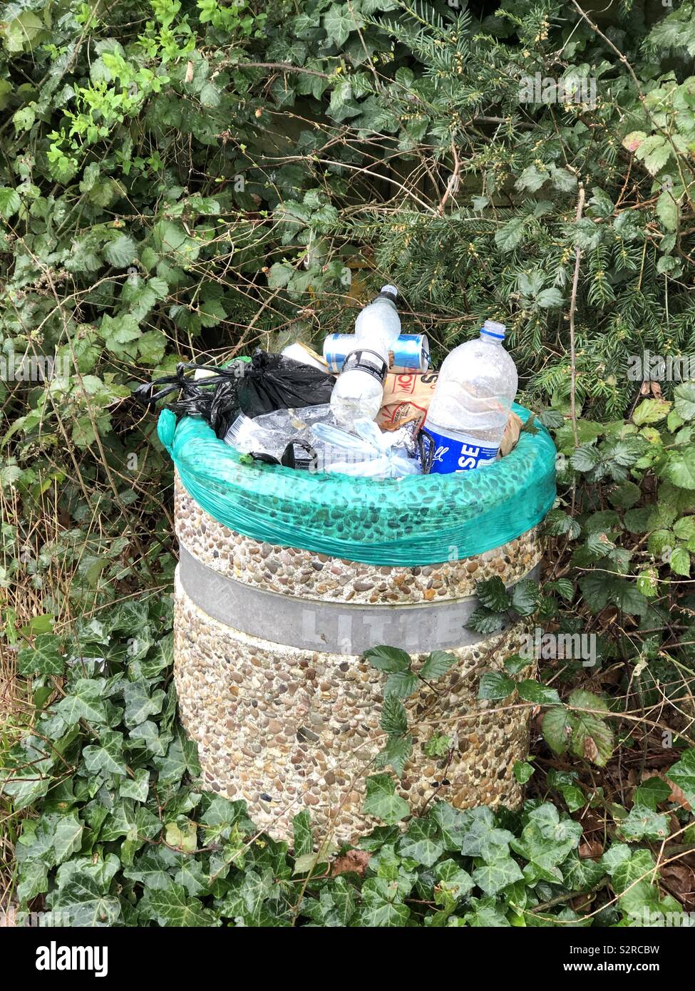 Waste bin overflowing with single-use plastic and other recycled items. - Smartphone Captured Stock Image