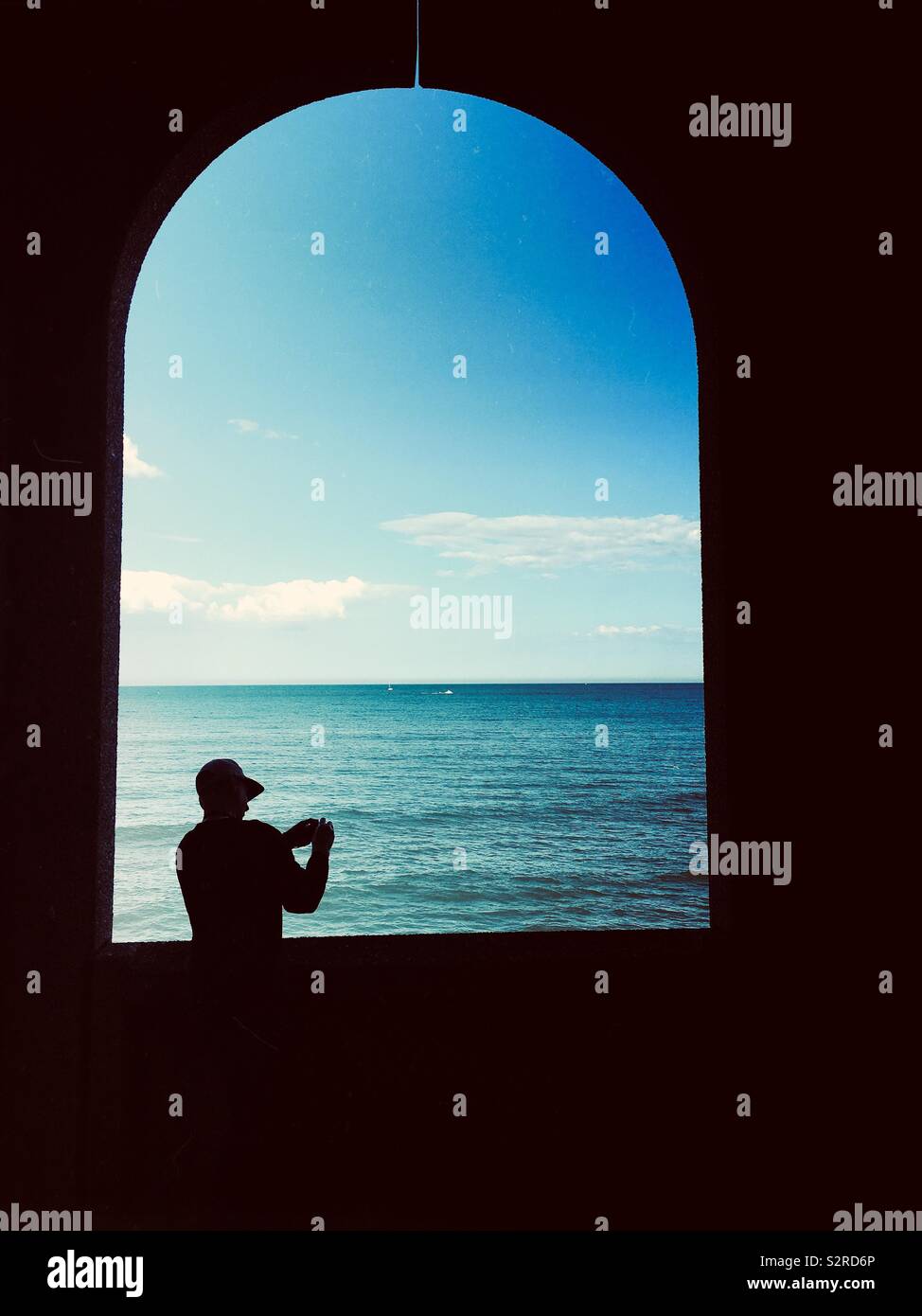 Silhouette of a man taking a photo of a seascape - Smartphone Captured Stock Image