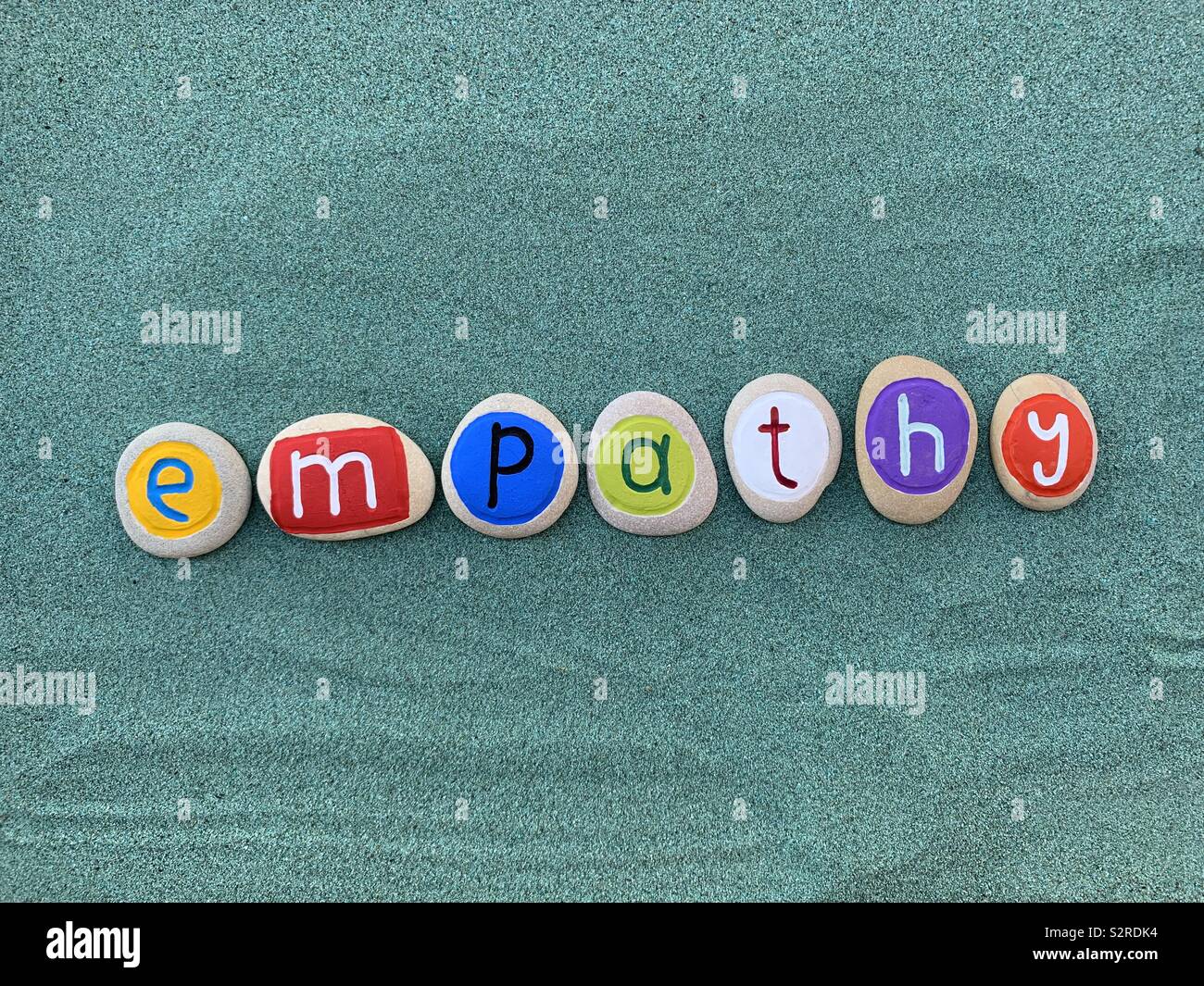 Empathy word composed over green sand with colored pebbles - Smartphone Captured Stock Image