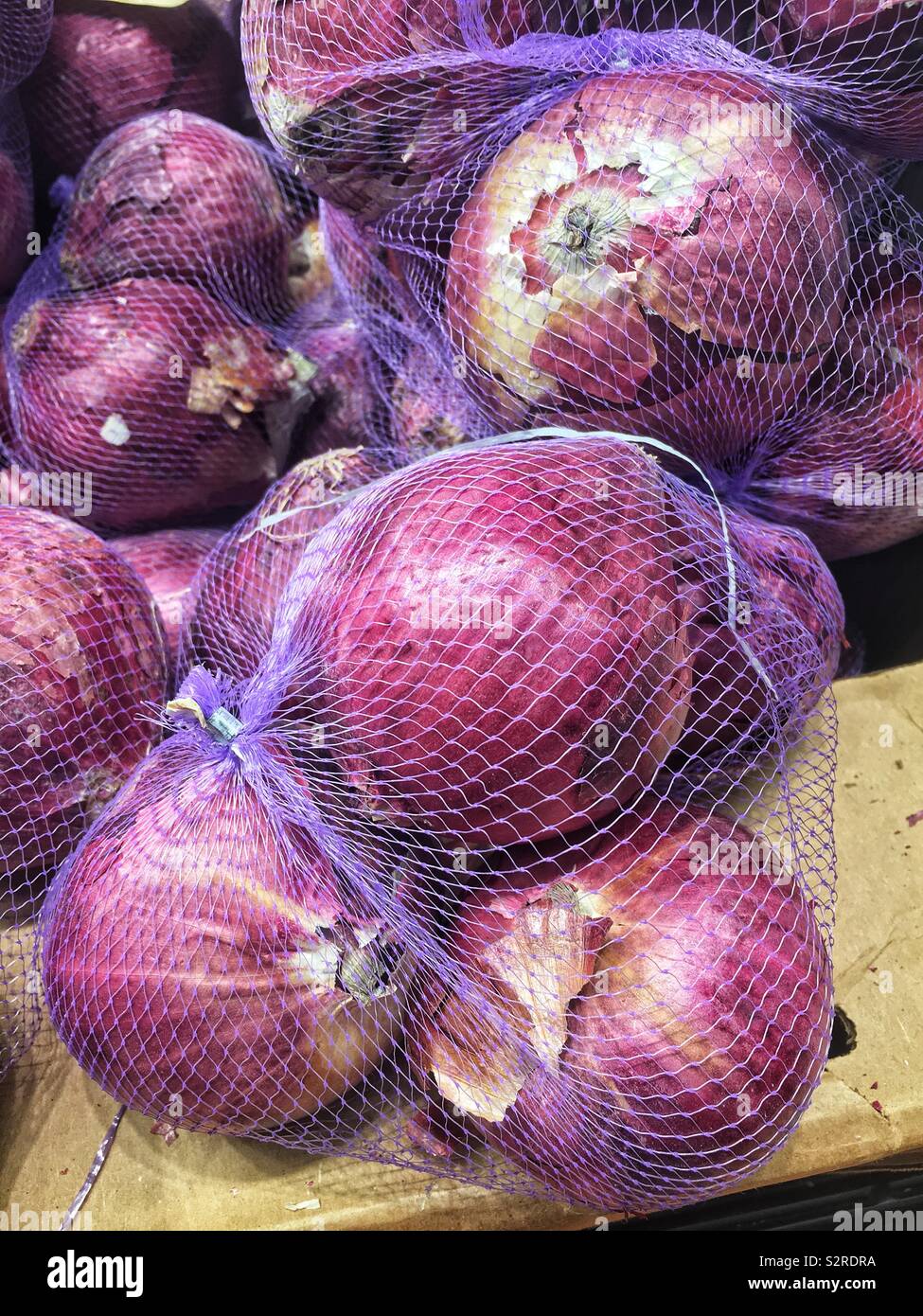 Purple plastic net bags of red onions. - Smartphone Captured Stock Image